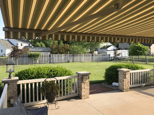A Sunesta awning stretches out across a Midwestern patio with a green view of the backyard space.